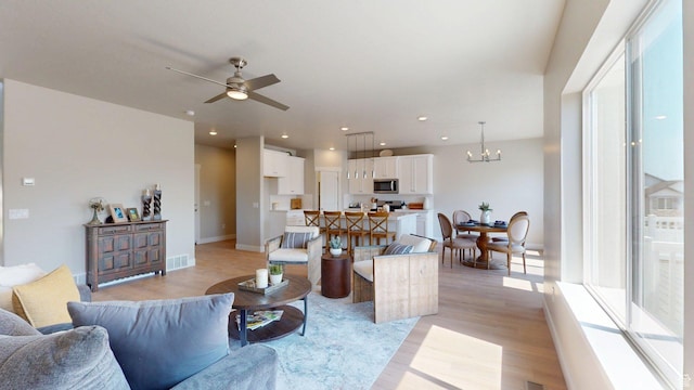 7497 W Sage Slope Way, Herriman, UT 84096 - living room featuring light wood-style flooring, a ceiling fan, a chandelier, and recessed lighting