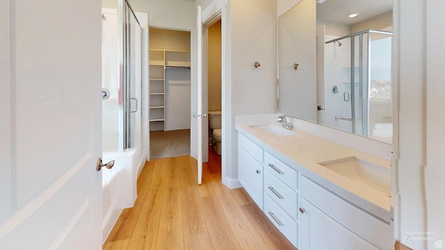 7497 W Sage Slope Way, Herriman, UT 84096 - bathroom featuring a stall shower, wood finished floors, double vanity, and a walk in closet