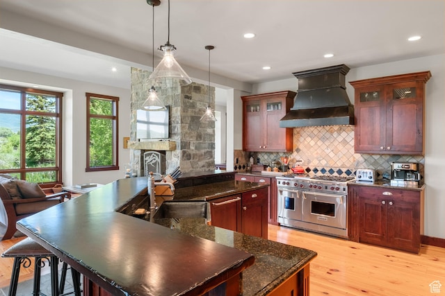 4445 N Millrace Rd, Oakley, UT 84055 - kitchen with premium range hood, stainless steel appliances, light wood finished floors, decorative backsplash, and hanging light fixtures