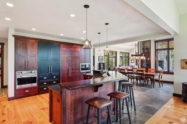 4445 N Millrace Rd, Oakley, UT 84055 - kitchen featuring stainless steel appliances, dark countertops, recessed lighting, a spacious island, and reddish brown cabinets