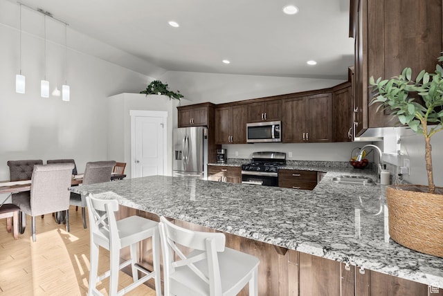 1235 N Valley Hills Blvd, Heber City, UT 84032 - kitchen featuring appliances with stainless steel finishes, vaulted ceiling, a peninsula, light stone countertops, and dark brown cabinetry