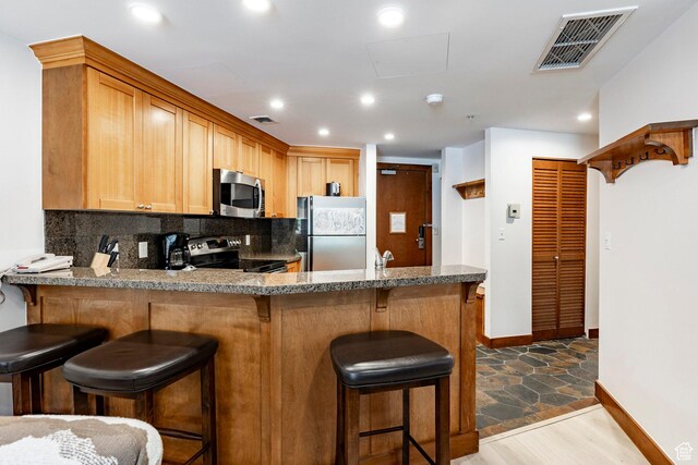 3720 N Sundial Ct Unit B322, Park City, UT 84098 - kitchen with appliances with stainless steel finishes, tasteful backsplash, a peninsula, recessed lighting, and a breakfast bar