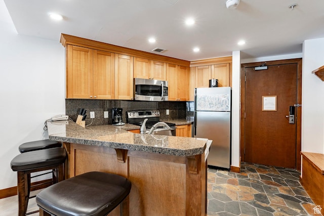 3720 N Sundial Ct Unit B322, Park City, UT 84098 - kitchen with appliances with stainless steel finishes, a peninsula, tasteful backsplash, a kitchen breakfast bar, and light countertops