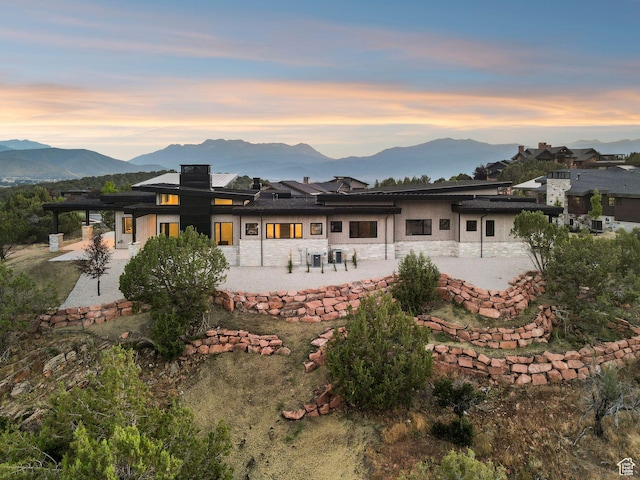 3057 E Corral Peak Cir Unit 147, Heber City, UT 84032 - back of house at dusk with a patio, stone siding, a mountain view, and stucco siding