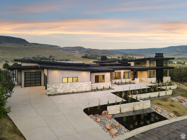 3057 E Corral Peak Cir Unit 147, Heber City, UT 84032 - back of property featuring stone siding, roof mounted solar panels, a garage, and a mountain view