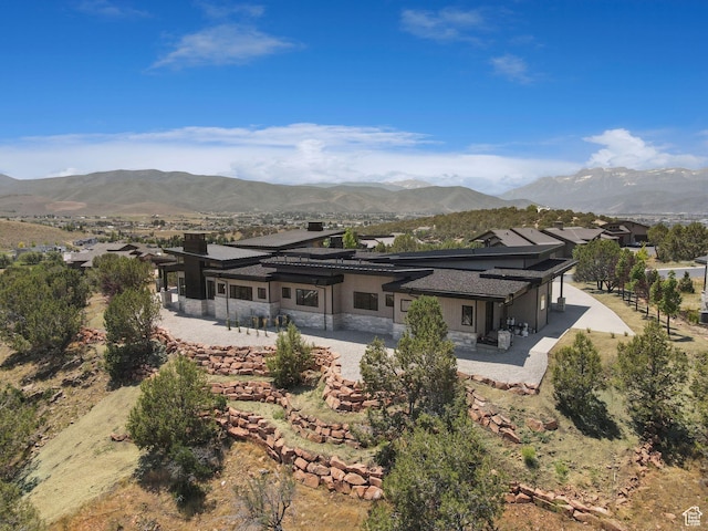 3057 E Corral Peak Cir Unit 147, Heber City, UT 84032 - rear view of house with stone siding, a patio area, a mountain view, stucco siding, and a chimney
