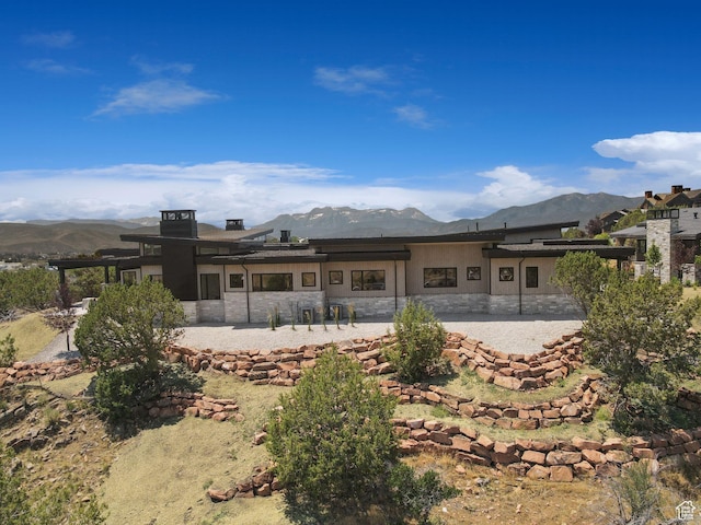 3057 E Corral Peak Cir Unit 147, Heber City, UT 84032 - rear view of house with stone siding, a mountain view, and a patio area