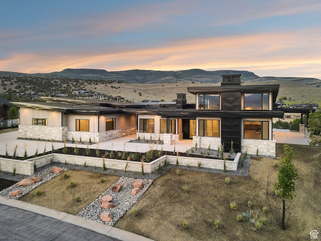 3057 E Corral Peak Cir Unit 147, Heber City, UT 84032 - rear view of house featuring stone siding, a patio, and a mountain view