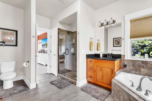 2330 E Meadow Lark Ln, North Logan, UT 84341 - full bathroom featuring vanity, a shower stall, a garden tub, and wood finished floors