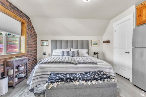 2330 E Meadow Lark Ln, North Logan, UT 84341 - bedroom featuring freestanding refrigerator, lofted ceiling, light wood-style flooring, and brick wall
