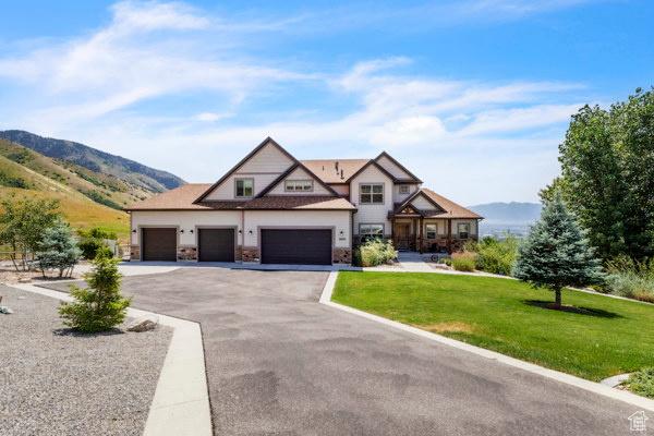 2330 E Meadow Lark Ln, North Logan, UT 84341 - view of front of home featuring a front yard, a mountain view, stone siding, driveway, and an attached garage