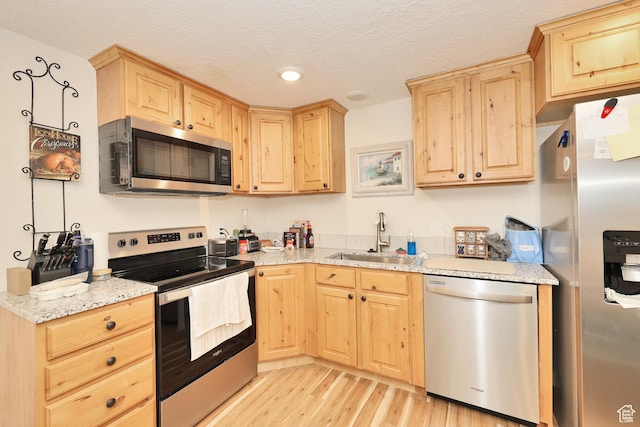 926 N 150 W, American Fork, UT 84003 - kitchen with stainless steel appliances, light brown cabinets, light wood-style flooring, a textured ceiling, and light stone counters
