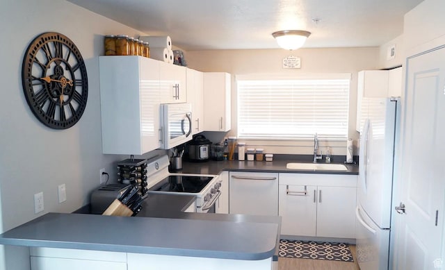 1055 W 1033 N Unit 301, Orem, UT 84057 - kitchen with white appliances, white cabinets, dark countertops, and a peninsula