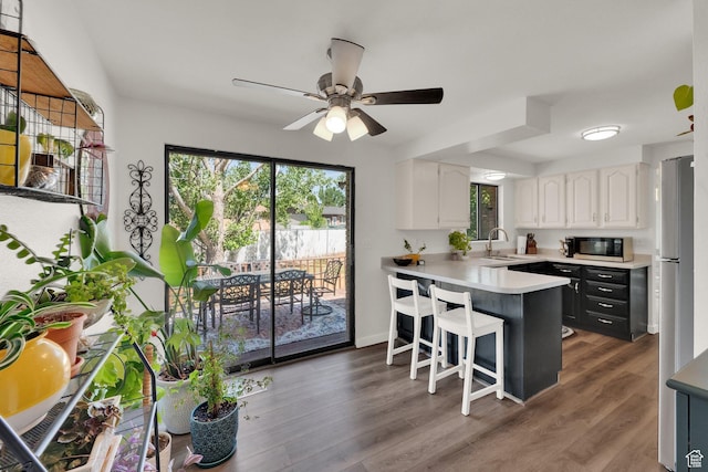1888 W 7265 S, West Jordan, UT 84084 - kitchen with black microwave, white cabinetry, healthy amount of natural light, and a peninsula