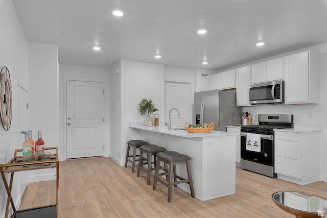 1529 E 720 N Unit 1065, Salem, UT 84653 - kitchen with stainless steel appliances, a kitchen breakfast bar, light wood-type flooring, light countertops, and white cabinetry