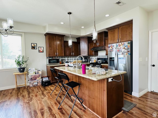10227 Mystic Brook Way S, South Jordan, UT 84095 - kitchen featuring stainless steel appliances, under cabinet range hood, backsplash, wood finished floors, and dark brown cabinetry