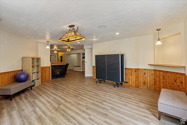2602 W 11625 S, Riverton, UT 84095 - exercise area featuring a fireplace, wainscoting, a textured ceiling, wood walls, and light wood finished floors