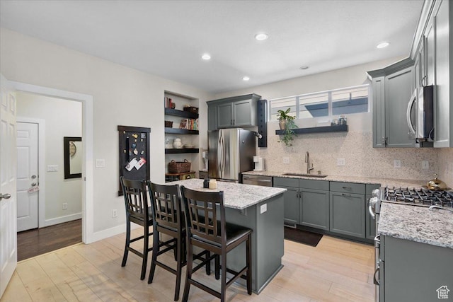 10848 S Tahoe Way S, Jordan, UT 84009 - kitchen with stainless steel appliances, a center island, light stone counters, a breakfast bar, and light wood-style flooring