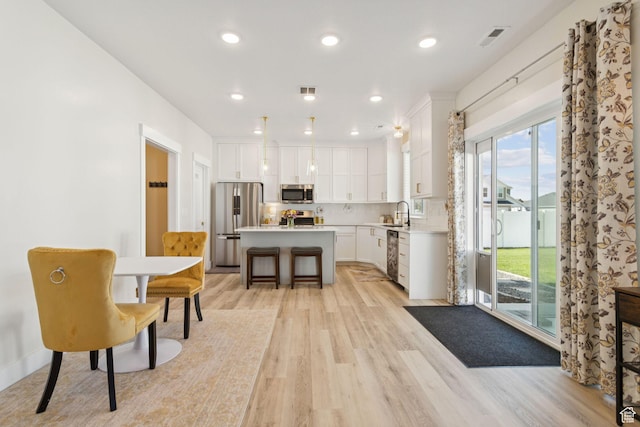 910 W 800 N, Tremonton, UT 84337 - kitchen with stainless steel appliances, light wood-style flooring, a kitchen island, light countertops, and white cabinets