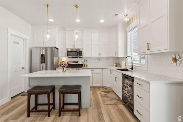 910 W 800 N, Tremonton, UT 84337 - kitchen with appliances with stainless steel finishes, a kitchen bar, light wood-style flooring, white cabinetry, and recessed lighting