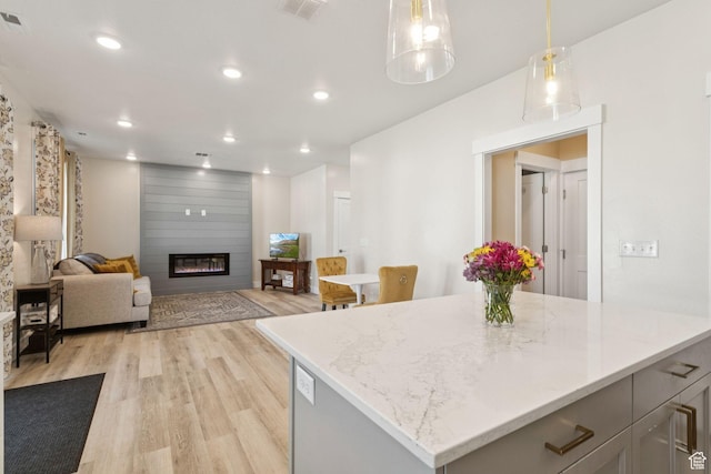 910 W 800 N, Tremonton, UT 84337 - kitchen with light wood-type flooring, a fireplace, recessed lighting, decorative light fixtures, and light stone countertops