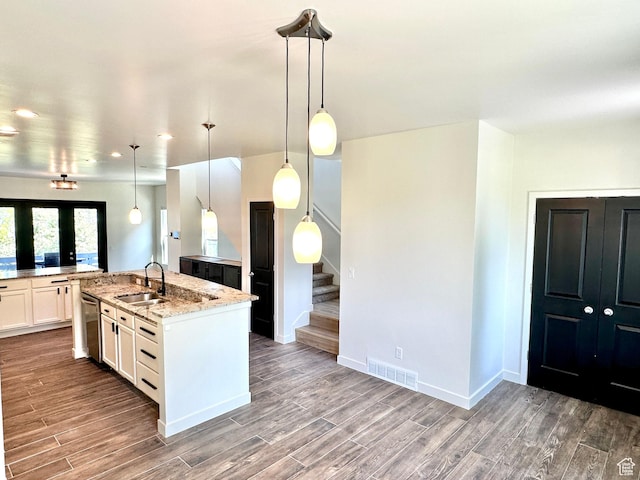 4843 W S Jordan Pkwy S, South Jordan, UT 84009 - kitchen with wood finished floors, an island with sink, light stone countertops, white cabinetry, and dishwasher