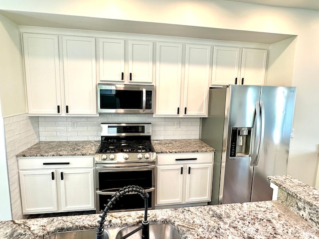 4843 W S Jordan Pkwy S, South Jordan, UT 84009 - kitchen with appliances with stainless steel finishes, decorative backsplash, light stone countertops, and white cabinetry