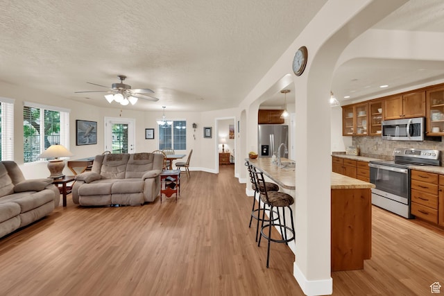 1225 W Dallin Dr Unit Q102, Pleasant Grove, UT 84062 - living area with light wood-style floors, arched walkways, a ceiling fan, and a textured ceiling