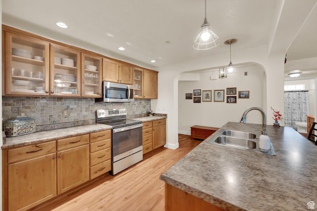 1225 W Dallin Dr Unit Q102, Pleasant Grove, UT 84062 - kitchen featuring appliances with stainless steel finishes, arched walkways, tasteful backsplash, light wood-type flooring, and hanging light fixtures