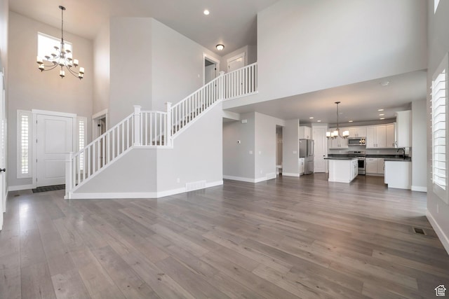 3552 W 2950 N, Lehi, UT 84043 - unfurnished living room featuring a chandelier, a high ceiling, stairs, dark wood-type flooring, and recessed lighting