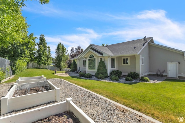 1630 N Camelot Dr E, North Logan, UT 84341 - rear view of house with a vegetable garden, a patio area, stucco siding, and roof with shingles