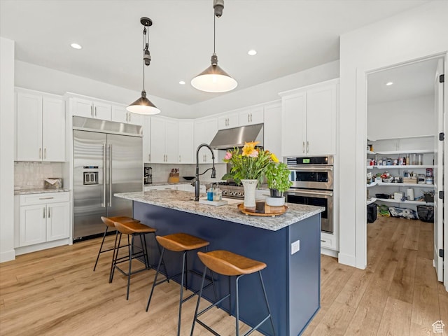 5796 N Valley View Rd, Lehi, UT 84043 - kitchen featuring stainless steel appliances, decorative backsplash, white cabinets, light wood-type flooring, and an island with sink