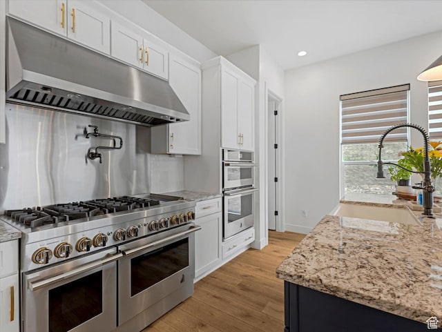 5796 N Valley View Rd, Lehi, UT 84043 - kitchen with stainless steel appliances, under cabinet range hood, light wood-type flooring, white cabinets, and recessed lighting