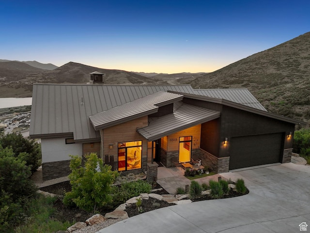 11515 N White Tail Ct, Hideout, UT 84036 - view of front of house with a standing seam roof, stone siding, an attached garage, driveway, and a mountain view