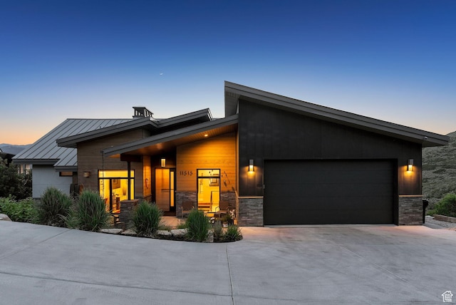 11515 N White Tail Ct, Hideout, UT 84036 - modern home featuring an attached garage, concrete driveway, stone siding, and a standing seam roof