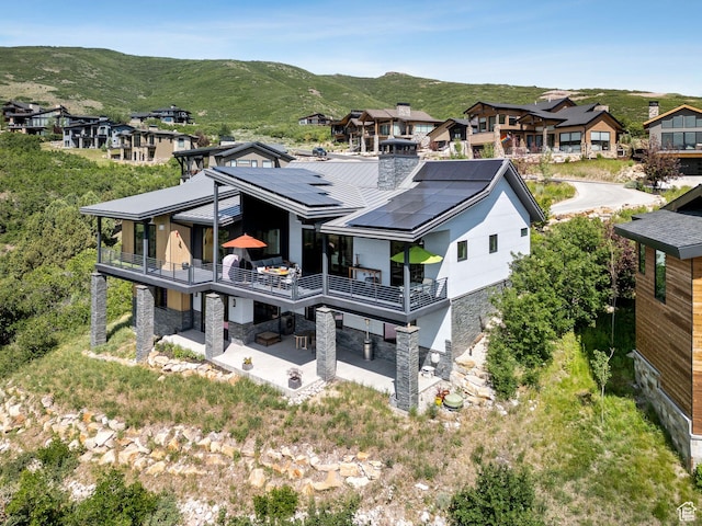 11515 N White Tail Ct, Hideout, UT 84036 - back of property with stone siding, a patio area, a mountain view, a chimney, and a balcony