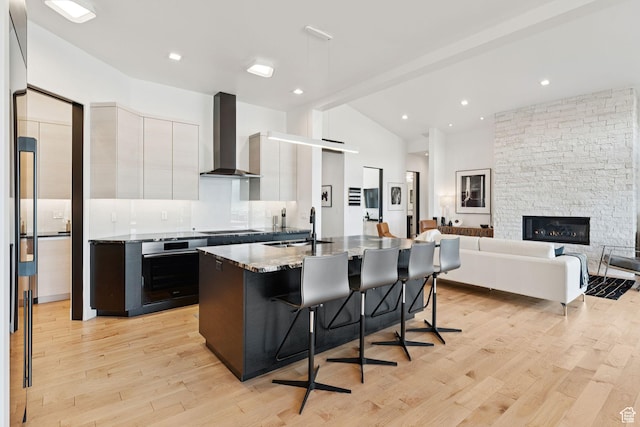 11515 N White Tail Ct, Hideout, UT 84036 - kitchen with wall chimney range hood, oven, white cabinetry, vaulted ceiling, and a breakfast bar area