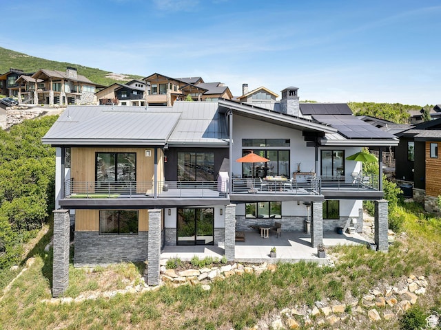 11515 N White Tail Ct, Hideout, UT 84036 - rear view of house featuring a patio area, a balcony, stone siding, and solar panels