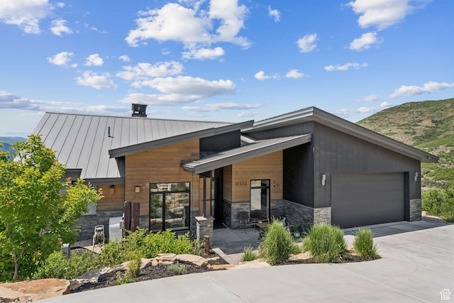 11515 N White Tail Ct, Hideout, UT 84036 - contemporary home with a standing seam roof, stone siding, a mountain view, concrete driveway, and a metal roof