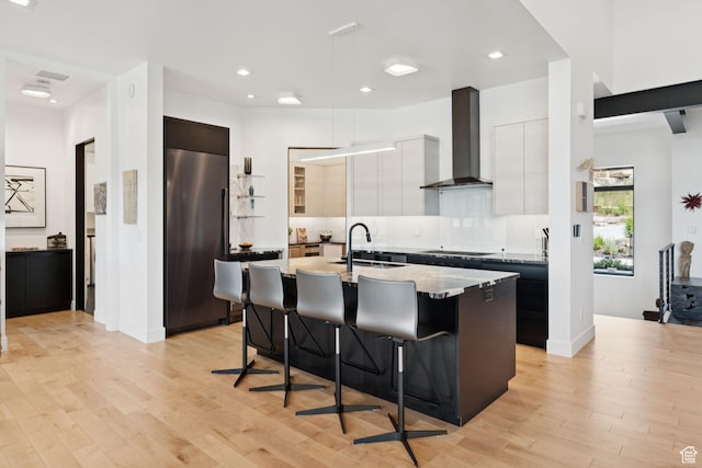 11515 N White Tail Ct, Hideout, UT 84036 - kitchen featuring high end refrigerator, wall chimney range hood, modern cabinets, a kitchen bar, and a center island with sink