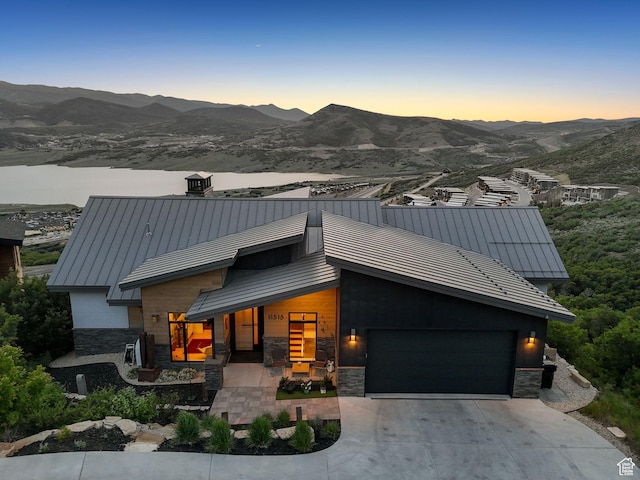 11515 N White Tail Ct, Hideout, UT 84036 - contemporary house with stone siding, a standing seam roof, a mountain view, a garage, and covered porch