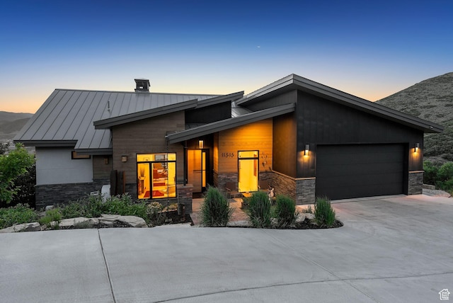 11515 N White Tail Ct, Hideout, UT 84036 - contemporary house with a standing seam roof, stone siding, an attached garage, concrete driveway, and a metal roof