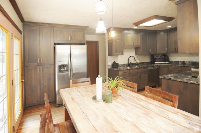 136 E 700 S, Farmington, UT 84025 - kitchen featuring appliances with stainless steel finishes, decorative backsplash, light wood-type flooring, a textured ceiling, and dark stone counters