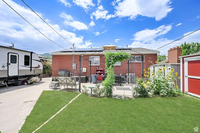 3347 S Rulon St W, Magna, UT 84044 - rear view of property featuring a patio area, solar panels, brick siding, and a lawn