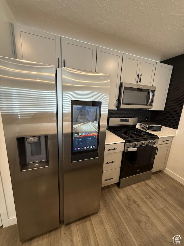 1144 E Trident Dr S, Saratoga Springs, UT 84045 - kitchen with stainless steel appliances, light wood-style floors, light countertops, and a textured ceiling