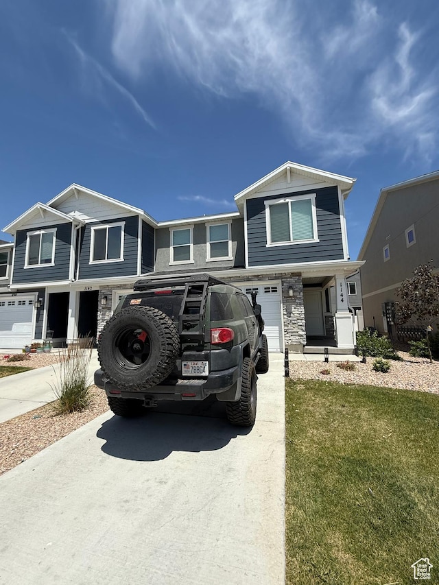 1144 E Trident Dr S, Saratoga Springs, UT 84045 - view of property with concrete driveway, an attached garage, stone siding, and a front lawn