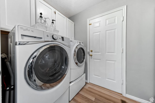 5149 W Village Wood Dr, West Valley City, UT 84120 - laundry room featuring washing machine and dryer, cabinet space, light wood-style flooring, and a textured ceiling