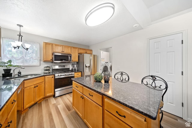 5149 W Village Wood Dr, West Valley City, UT 84120 - kitchen with appliances with stainless steel finishes, independent washer and dryer, light wood-style flooring, a kitchen island, and dark stone countertops