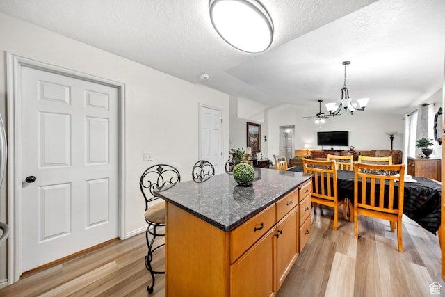5149 W Village Wood Dr, West Valley City, UT 84120 - kitchen with light wood-style floors, a chandelier, a kitchen island, a breakfast bar, and open floor plan