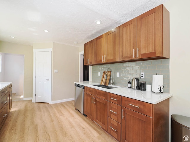 320 E Hollywood Ave S, Salt Lake City, UT 84115 - kitchen with stainless steel dishwasher, light wood-style floors, tasteful backsplash, brown cabinets, and light countertops